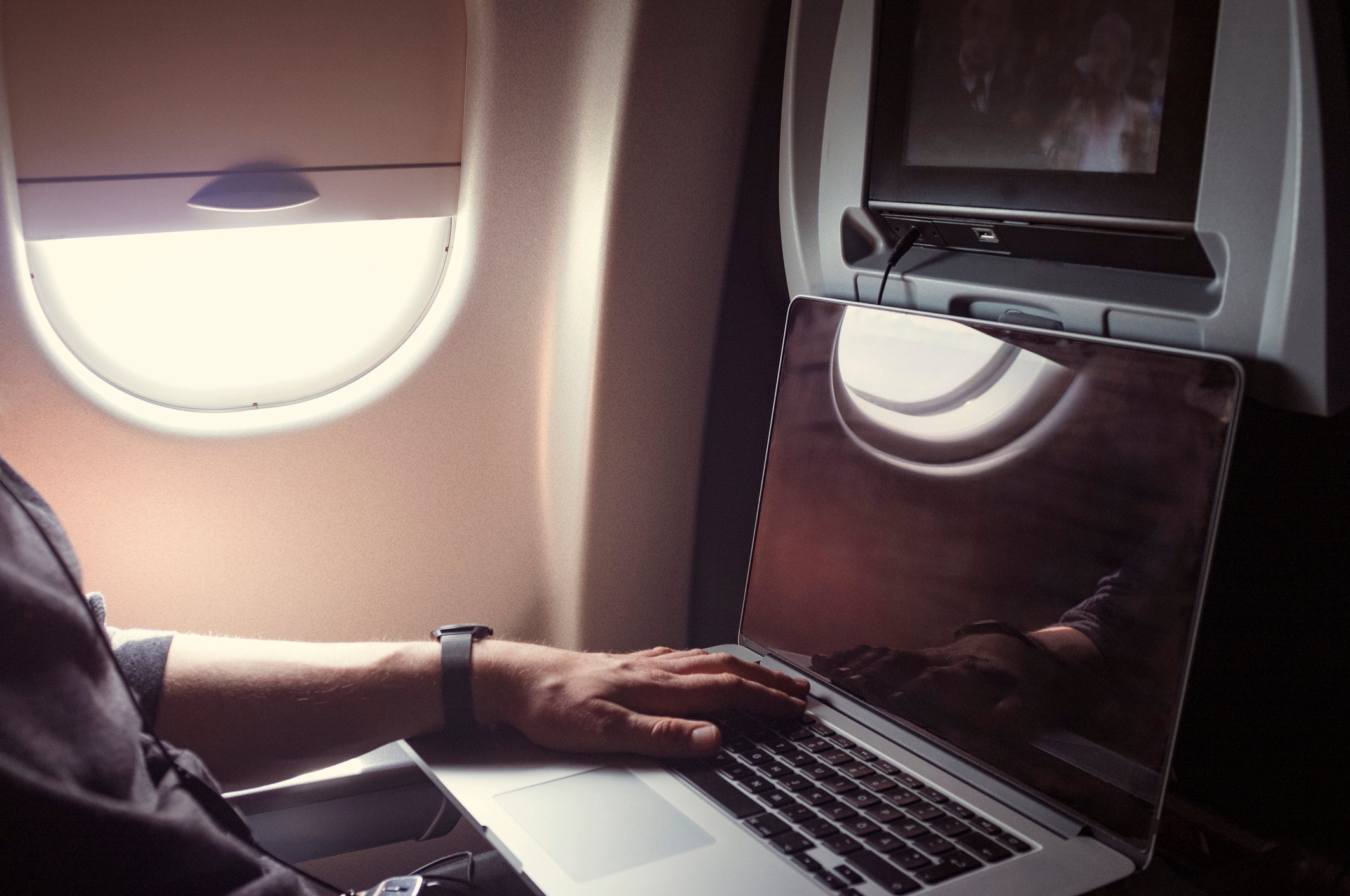 Cropped image of male passenger using laptop in airplane