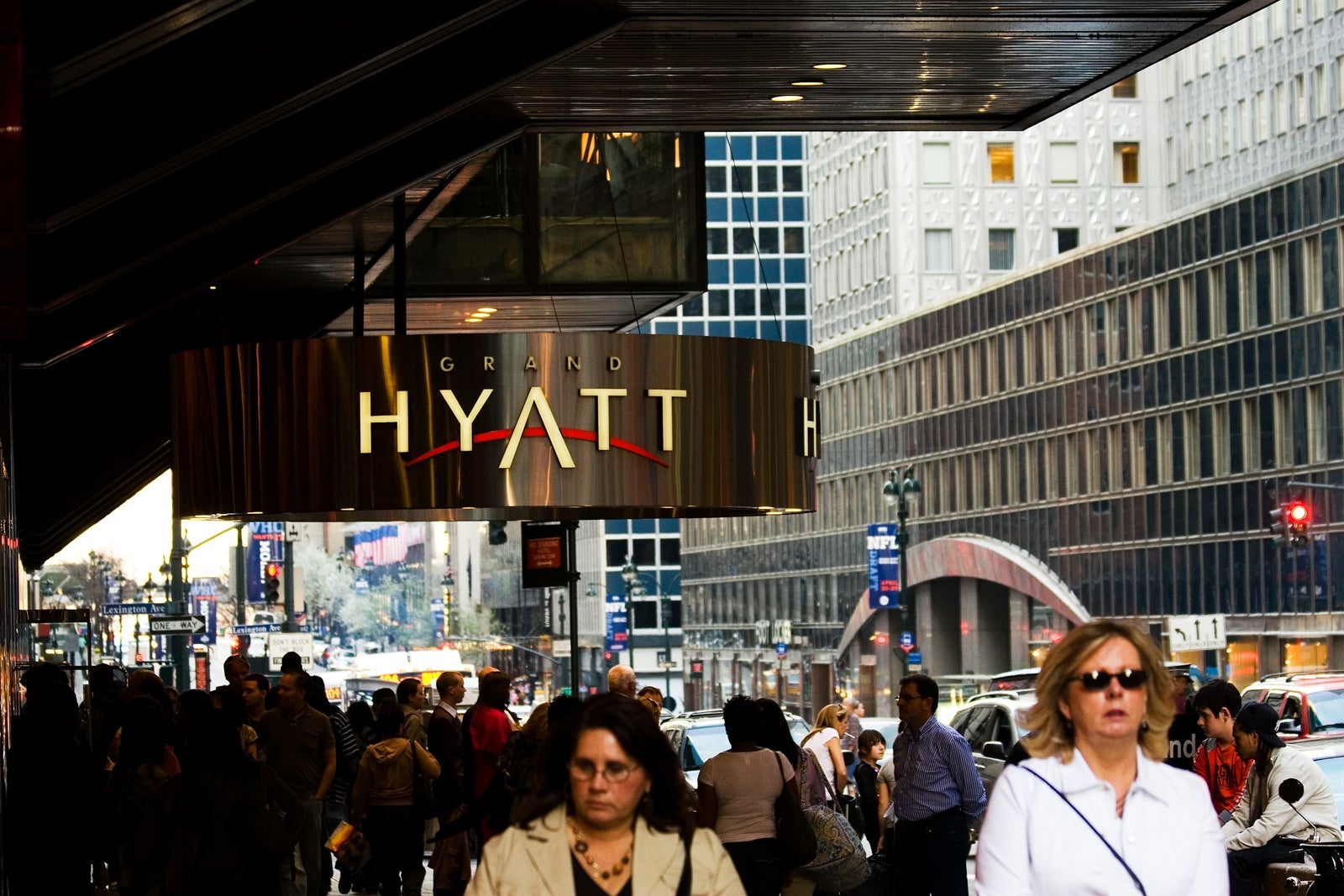 People on street outside Grand Hyatt hotel entrance, with Mobil Building to right, East 42nd Street, Midtown.