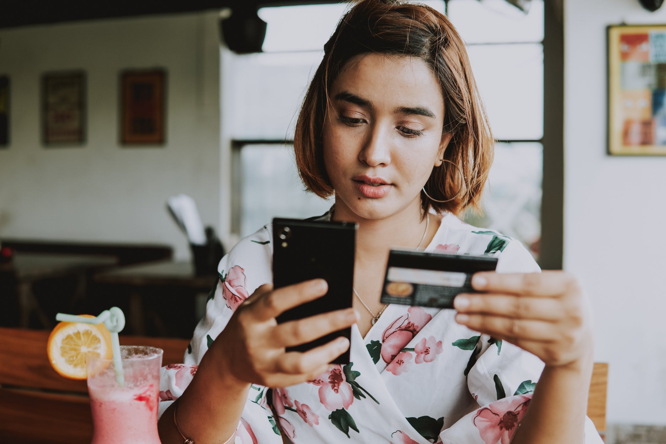 Young woman shopping online with smartphone and credit card on hand.