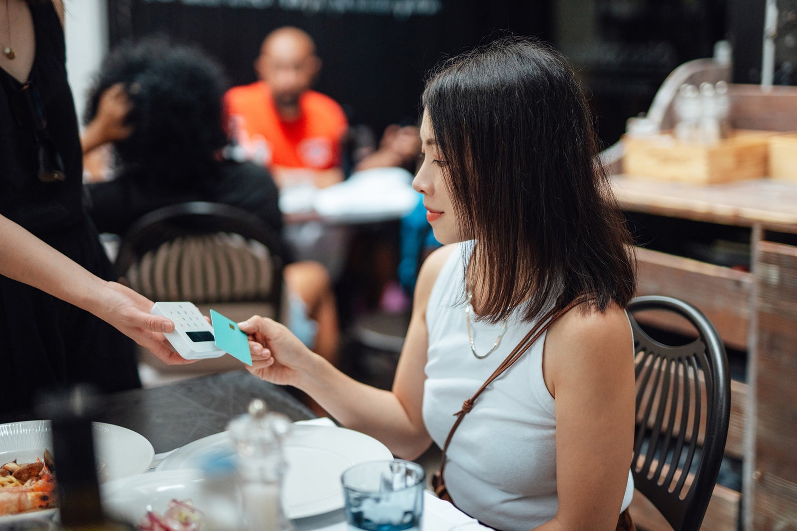 Young woman making contactless payment with credit card in restaurant
