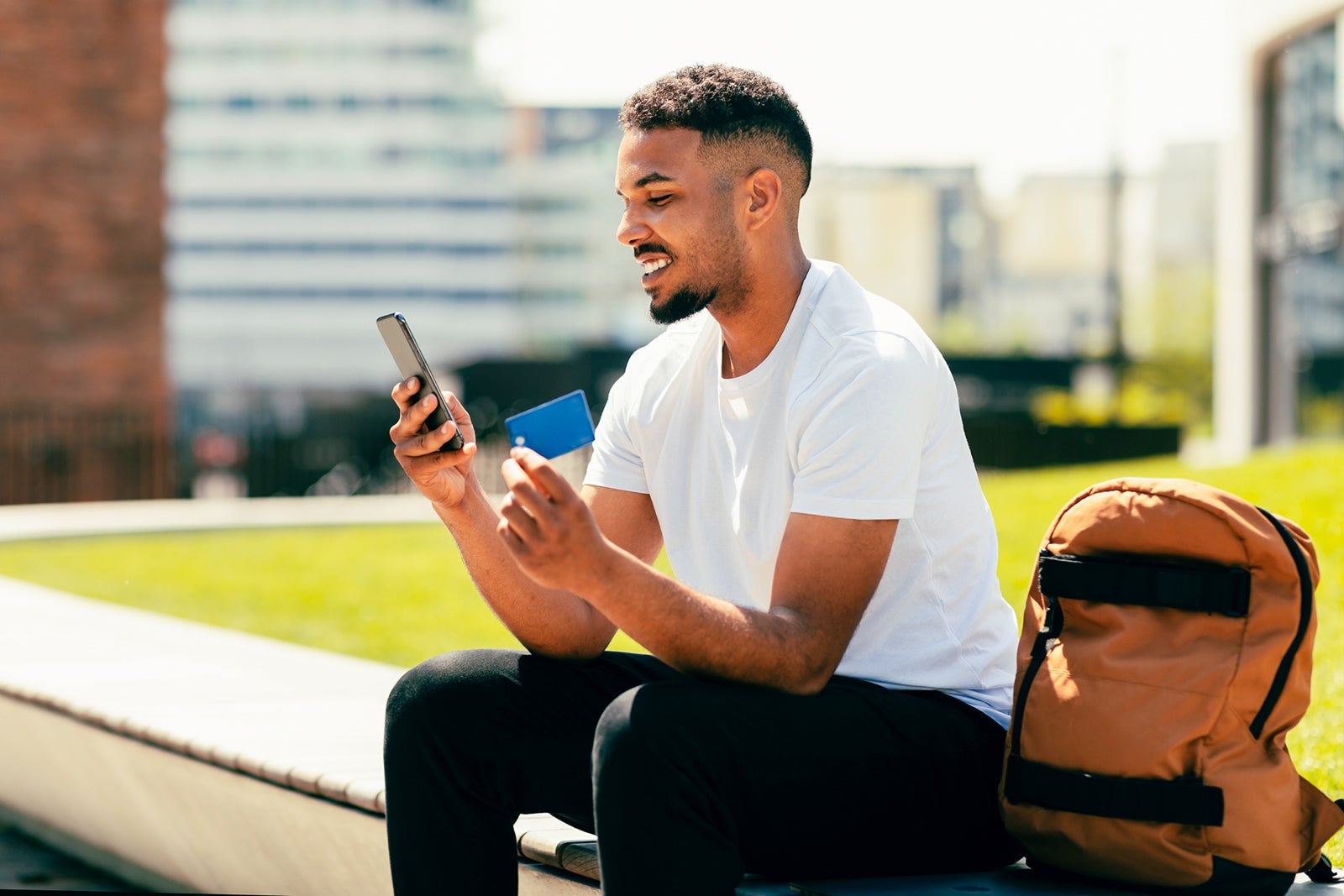 Technology, online payment and people concept. Excited black man with smartphone and credit card ordering goods outdoors