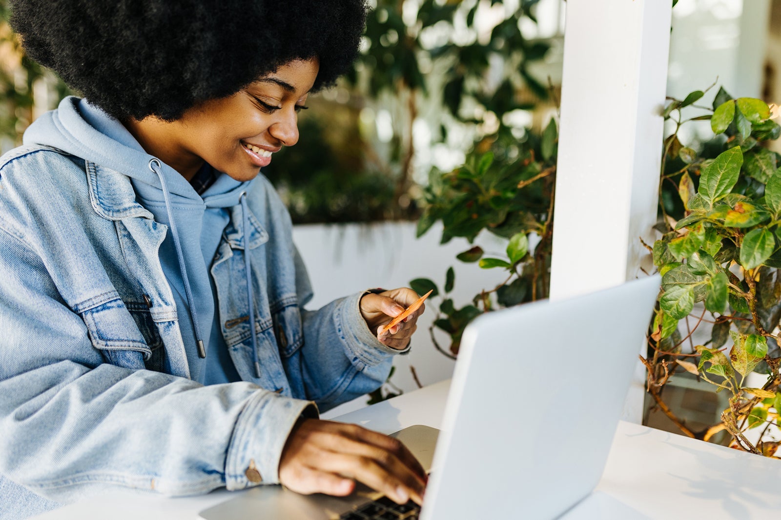 Afro woman holding a credit card and using laptop computer while