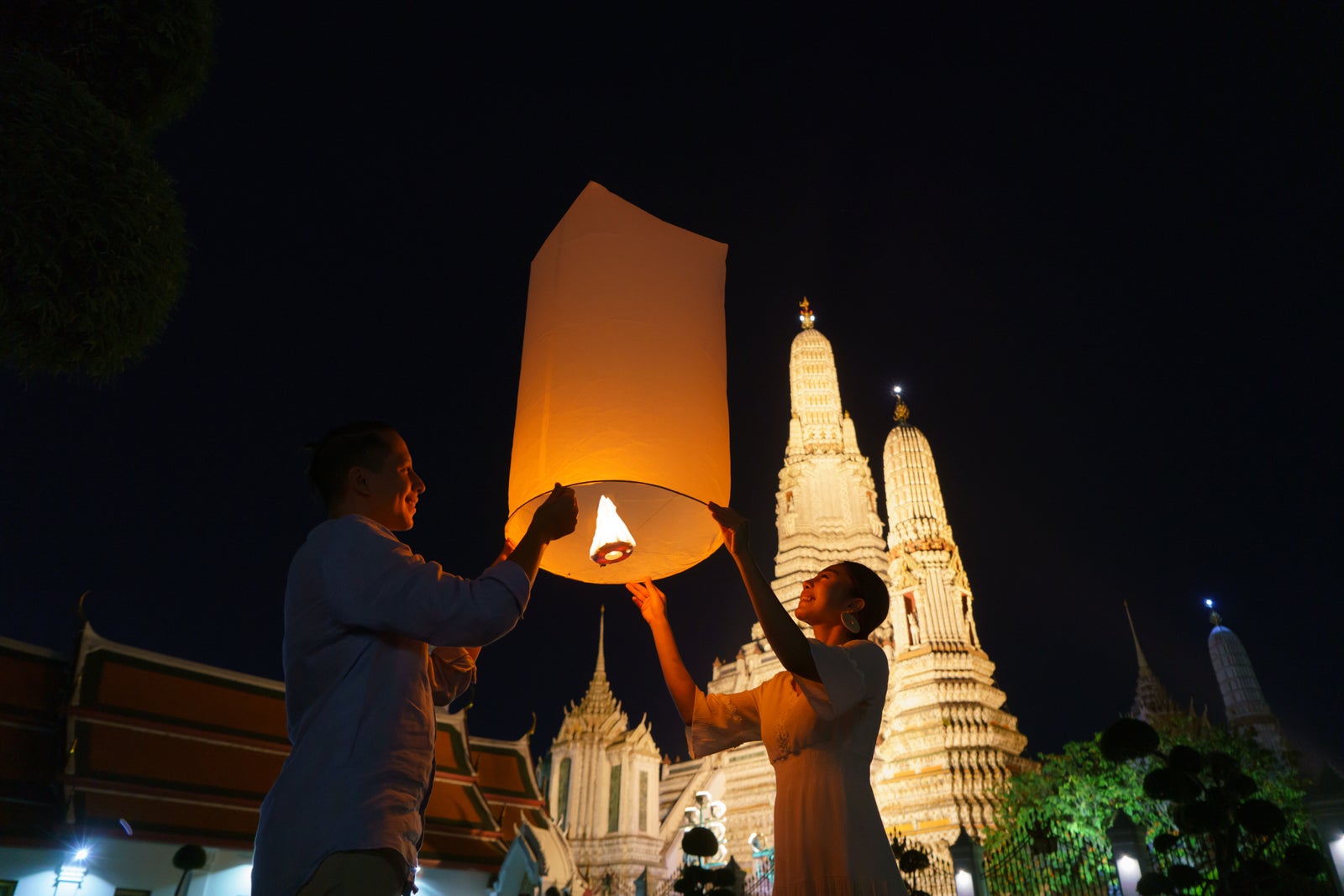 Mixed race romantic lover couple in Wat arun in night time and floating lamp in Yi Peng festival under Loy Krathong day, Bangkok city ,Thailand"r
