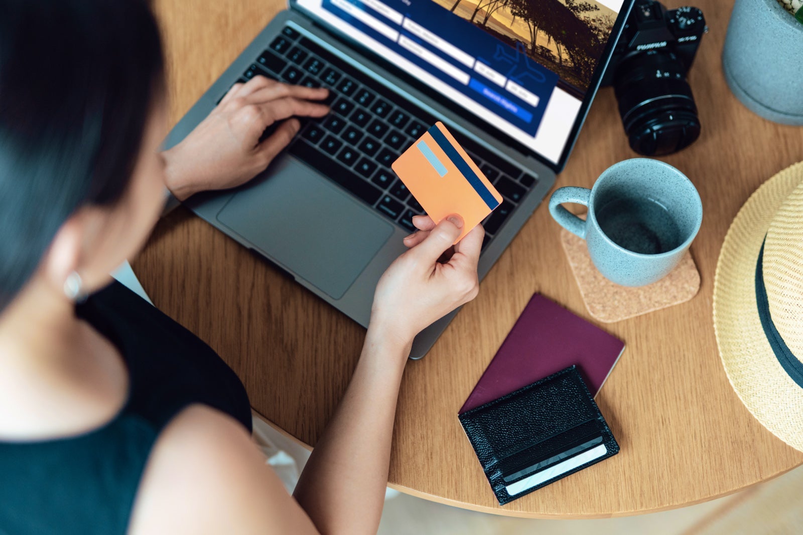 20241016_Credit Card Legislation Sponsored Article_Person holding credit card at home while looking at booking flights at home office