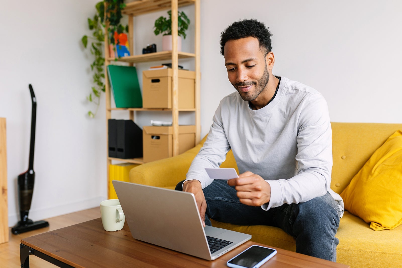 Young adult Latin American man typing credit card bank number on laptop computer e-commerce website. Online shooping, people and e-commerce concept
