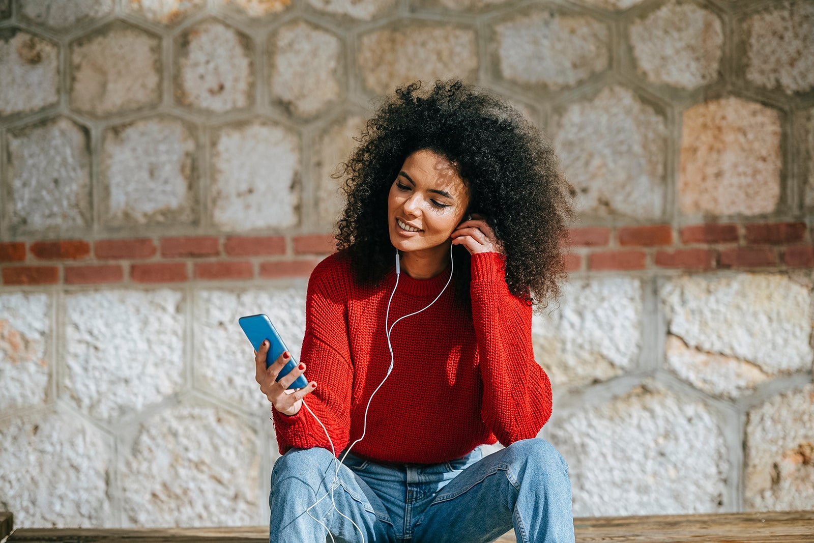 Woman with mobile phone and earphones outdoors.
