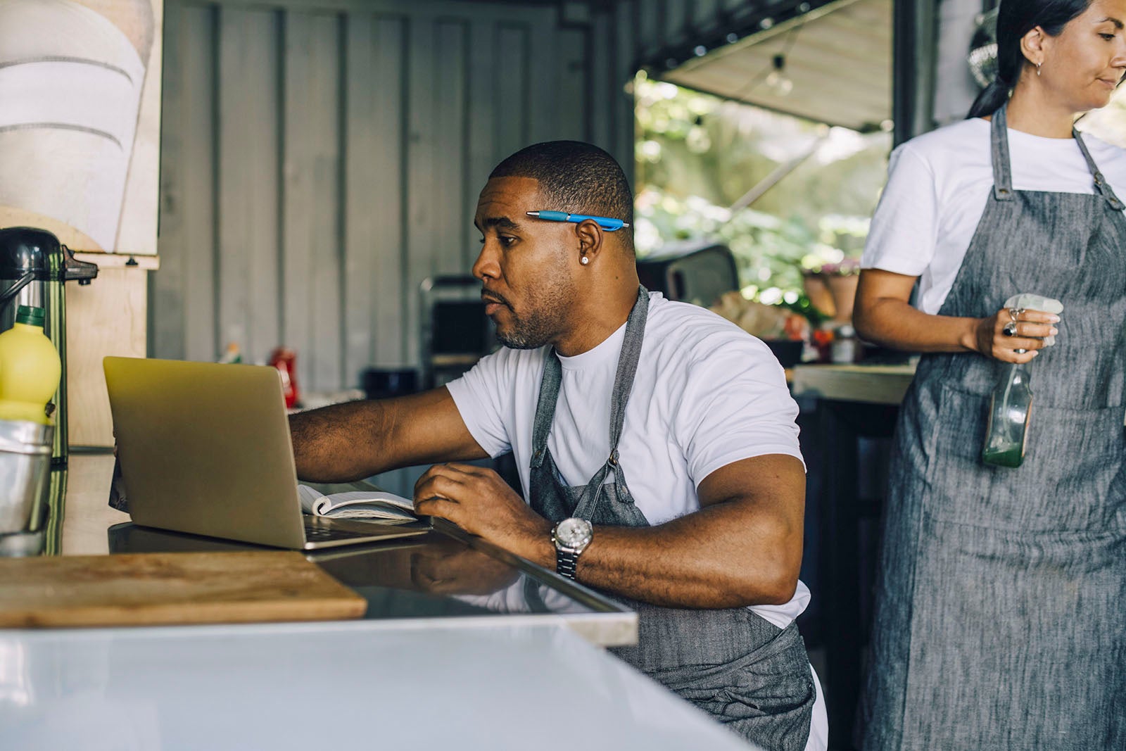 Mature male entrepreneur working on laptop by female colleague in food truck